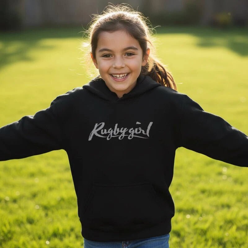 A Rugby Girl listing photo: a girl in the black Rugbygirl hoodie on a sunny lawn.