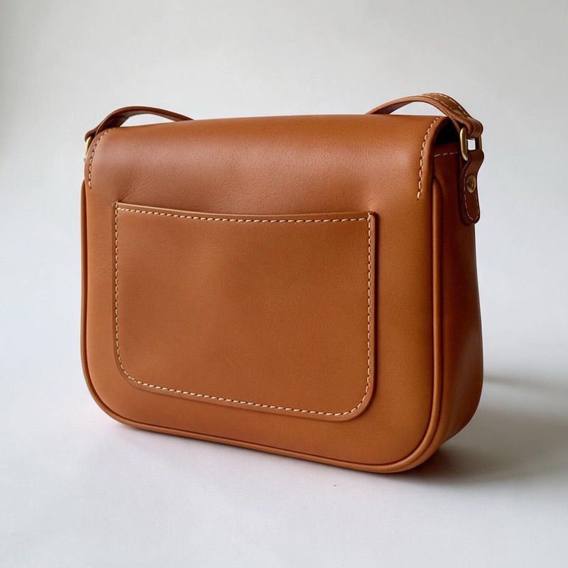 The same bag turned to show the slip pocket on its back and one side, against the same plain background.