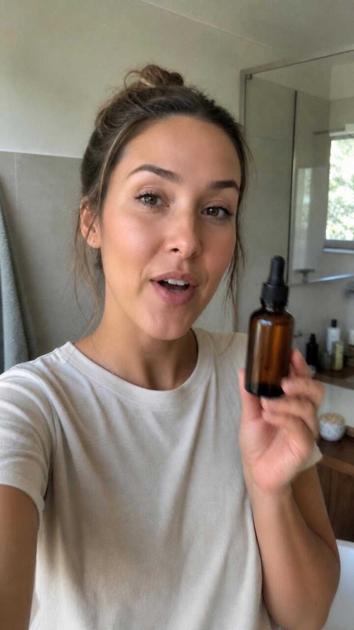 The same bottle held up to a phone camera by a woman talking in her bathroom.