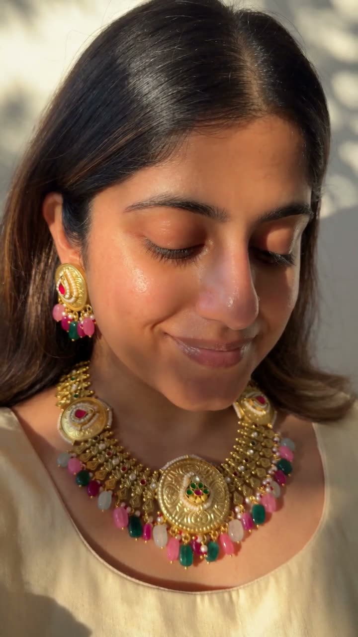 A gold-finish choker set lifted from its shipping sleeve, the pink and green drops turned in the hand, then worn with the matching earrings at golden hour.